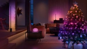 Christmas tree with multicolored smart lights in a living room, creating a soft ambient glow with festive decorations visible.