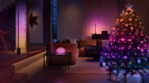Christmas tree with multicolored smart lights in a living room, creating a soft ambient glow with festive decorations visible.
