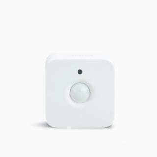 White square motion sensor with rounded edges, a central dome-shaped sensor, and a small circular indicator above it, matte finish.