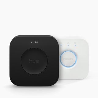 Two compact, square-shaped smart lighting bridges, one black with a matte finish, one white with a circular button and indicator lights.