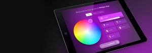Tablet displaying smart lighting app interface with color wheel, ""All lights"" slider, bulb and Hue Go buttons, and menu options.