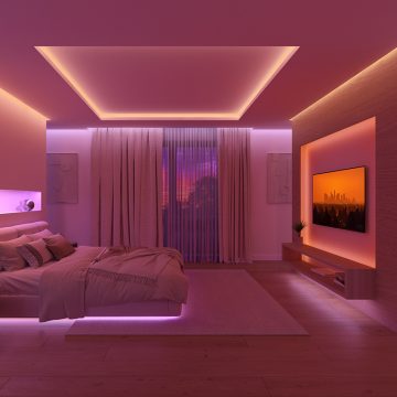 Un dormitorio iluminado con luz indirecta en tonos rosa y blanco cálido, gracias a tiras LED ocultas bajo la cama y detrás de cornisas en el techo y la pared, lo que crea un efecto de lavado de pared. 