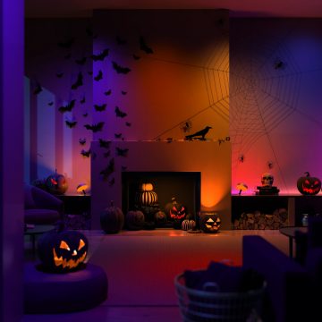 Luces inteligentes con capacidad de color de Philips Hue repartidas alrededor del salón en Halloween con calabazas naranjas que brillan intensamente