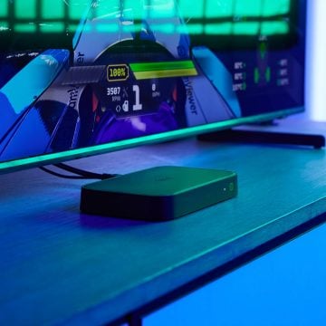 Una HDMI Sync box 8K sobre una consola de TV en una habitación con iluminación azul de entretenimiento.