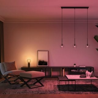 Salon avec une douce lueur d'ambiance en violet et orange, mettant en valeur la décoration et les œuvres d'art modernes. 