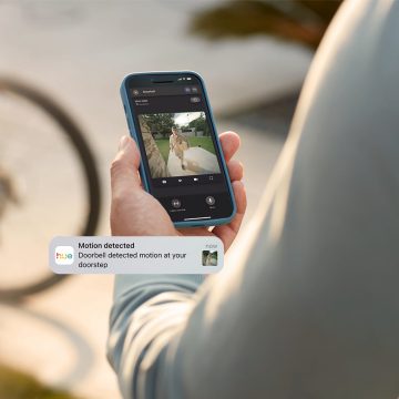 Une personne reçoit une notification de détection de mouvement et surveille sa porte d'entrée via l'application Hue pendant son absence. 