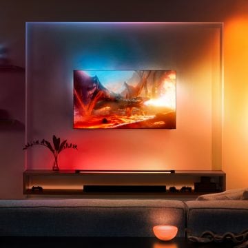 Une installation TV avec éclairage immersif Hue comprenant un Play light tube, des Hue Play gradient lightstrips et un éclairage d'accentuation portable Go