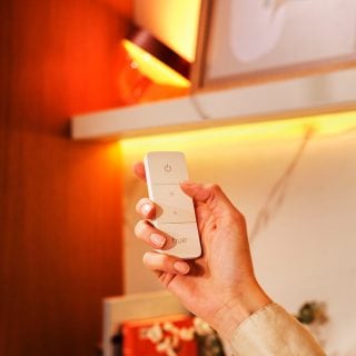 Une main qui tient une télécommande pour tamiser l’éclairage.