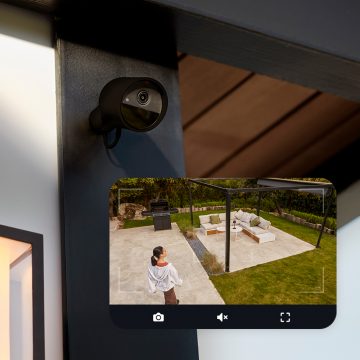 Une caméra Hue Secure fixée à un mur et une image en direct de la caméra montrant une femme dans une arrière-cour.