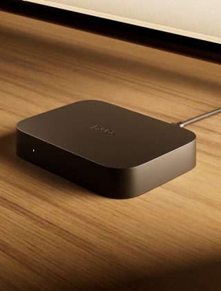 Un boîtier de synchronisation Philips Hue Play 4K placé sur une installation de divertissement devant un téléviseur. 