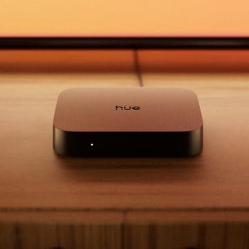 Un boîtier de synchronisation Philips Hue Play 4K placé sur une installation de divertissement devant un téléviseur.
