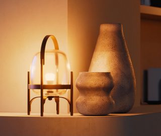 Une lampe de table en verre équipée d’une ampoule intelligente Philips Hue qui brille d’une lumière blanche et chaleureuse. 