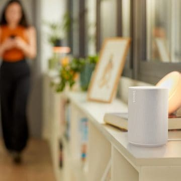 Un altoparlante connesso Sonos posizionato su un comodino e lampade e faretti smart Philips Hue che illuminano lo spazio