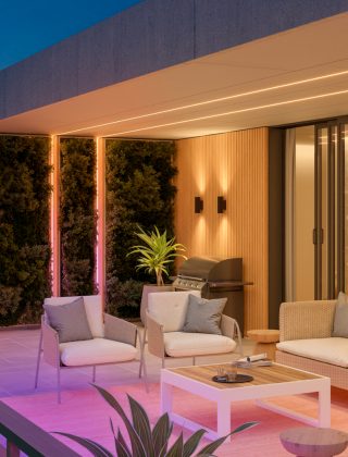 Twee Philips Hue OmniGlow buiten LED strips zijn geïnstalleerd langs de muur en het plafond en verlichten het terras met uniforme kleurverlopen van roze en geel licht.