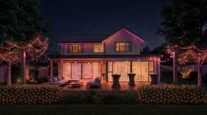 De gevel en de achtertuin van een huis versierd met Festavia LED ijspegelverlichting, gordijnverlichting, netverlichting en globe lampen, die schijnen in verlopen van roze, paars en wit licht. 