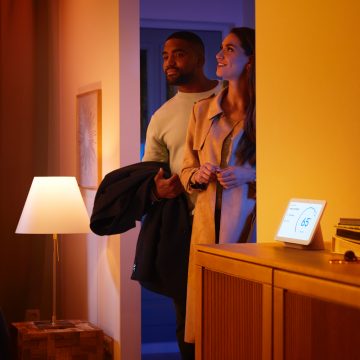 Man en vrouw die een huis met een slimme speaker binnenlopen 