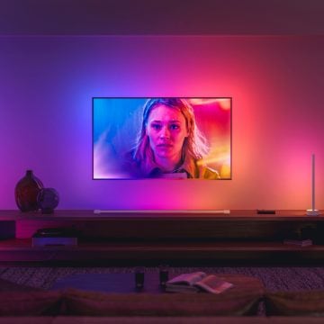LG-tv hangend aan de muur in de woonkamer omgeven door gekleurde lampen 