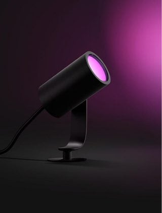 Een zwarte Philips Hue Lily spot die roze licht uitstraalt. 
