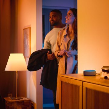 Man en vrouw die een huis met een slimme speaker binnenlopen 