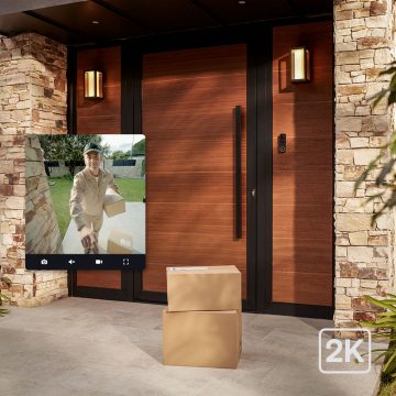 Ei inngangsdør med en levering av esker og et innfelt bilde som viser leveringspersonen via en Hue Video Doorbell.