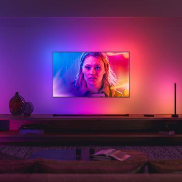 Telewizor zsynchronizowany z oświetleniem przestrzennym Philips Hue świeci odcieniami niebieskiego, różowego i czerwonego, dopasowując się do obrazu na ekranie.