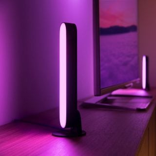 Två Play light bars placerade på vardera sidan av en TV-skärm som lyser i rosa smart ljus.