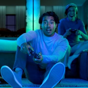 En gamer spelar ett spel med trippelskärm med hjälp av Hue gradient lighstrips och ljusskenor. 