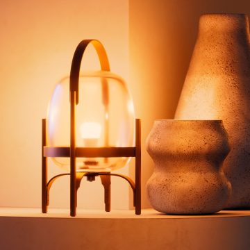 En A19-smartlampa monterad på en bordslampa i glas som lyser i varmvita toner med smart ljus